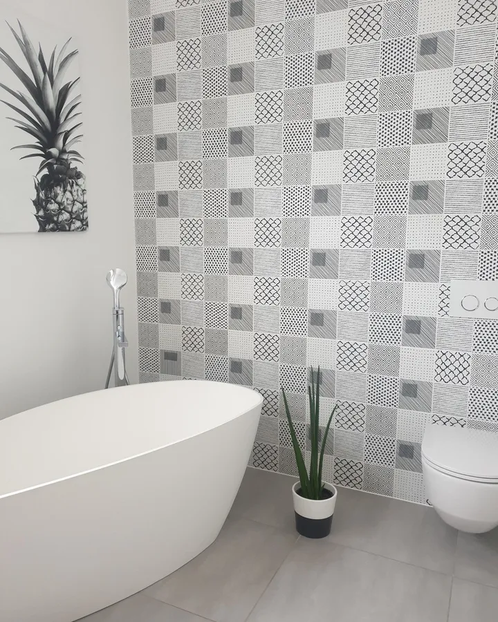 Salle de bains avec baignoire, paroi à motifs et finitions sanitaires blanches